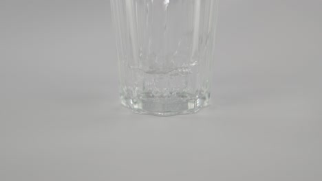 Stilles-Wasser-In-Zeitlupe,-Das-Vor-Neutralem-Hintergrund-In-Klares-Glas-Strömt