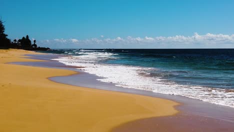 hd hawaii kauai slow motion static wide shot of beach on left and ocean waves washing in from right to left and across lower frame on a sunny day