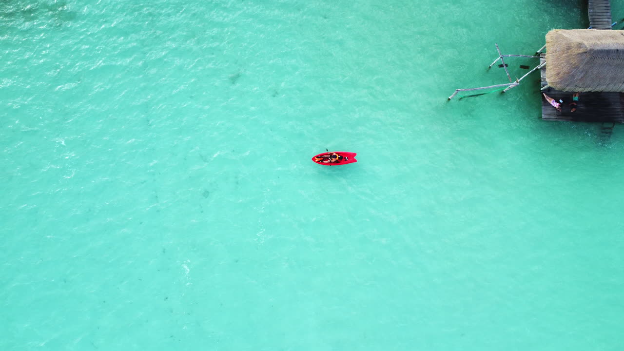 Aerial view of red kayak paddling in the lagoon, moving away from the coast