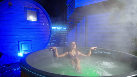 attractive relaxed caucasian woman in stripy swimsuit sits in the hot tub. beauty and spa procedures in winter.