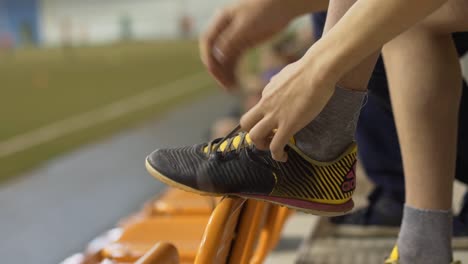 child tying shoelaces on soccer shoes in a stadium