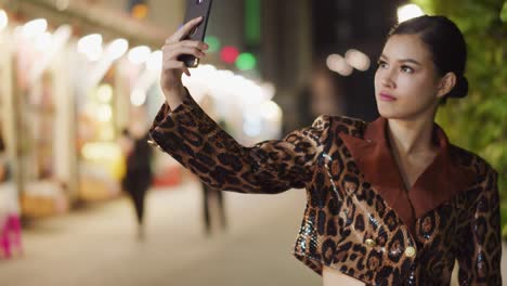 sunningly seductive asian girl wearing leopard print takes a selfie with her smartphone then posts it on social media