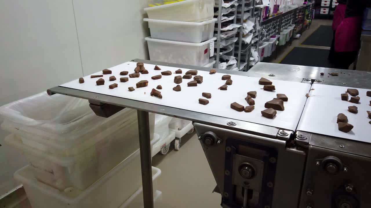 Broken Chocolate Pieces on Conveyor Belt in a Chocolate Factory