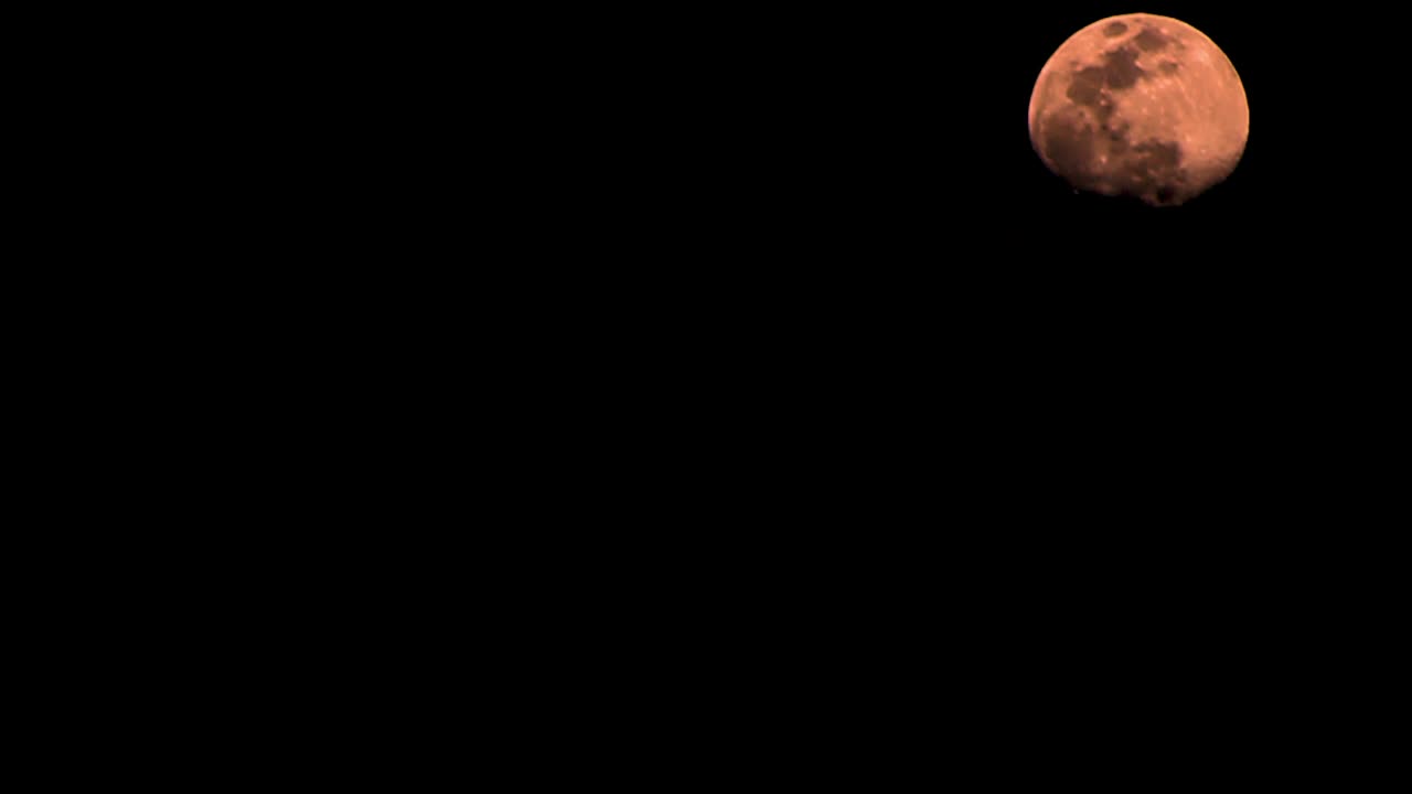 Orange moon time lapse, halloween, moon moves from bottom to top of screen.