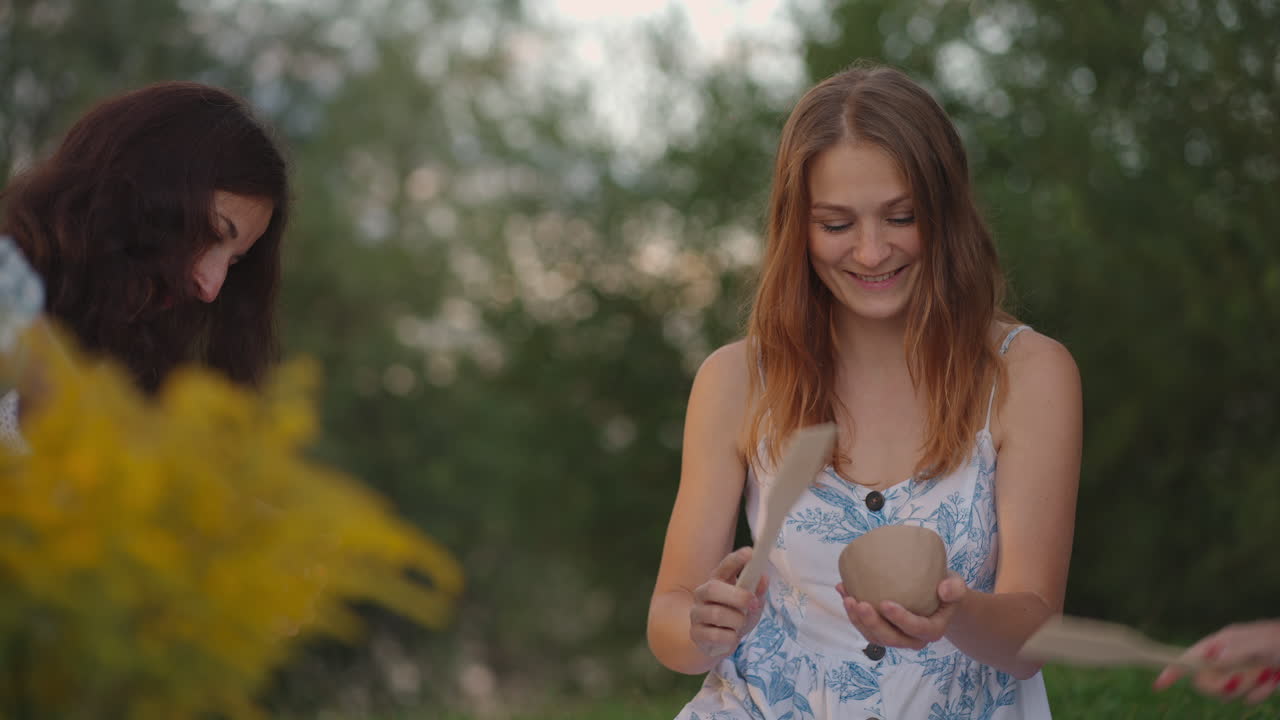 mujeres jóvenes en la naturaleza en el campo en el parque juntos esculpir arcilla con herramientas tocar productos de arcilla con palas. se comunican compartir sus impresiones. primer plano