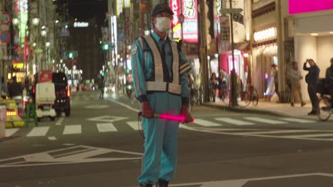 veteran traffic officer managing osaka streets with flashing red light stick