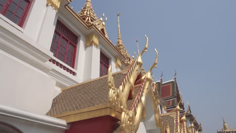 slow motion moving forward dolly under a gold and white buddhist temple pointing up of a popular travel destination in the city of bangkok in thailand