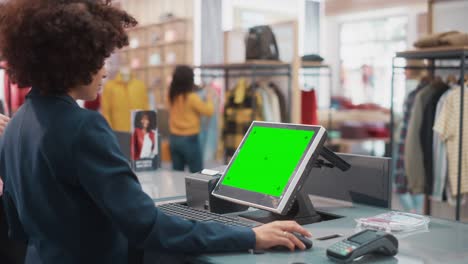 cajero de caja de la tienda de ropa: elegante gerente de ventas minoristas femenina con cabello afro trabajando en un cajero automático con caja registradora de dinero computadora con pantalla verde pantalla de chroma simulacro de llave.