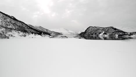 drone aerial shot of a frozen lake in tromso, norway during winter