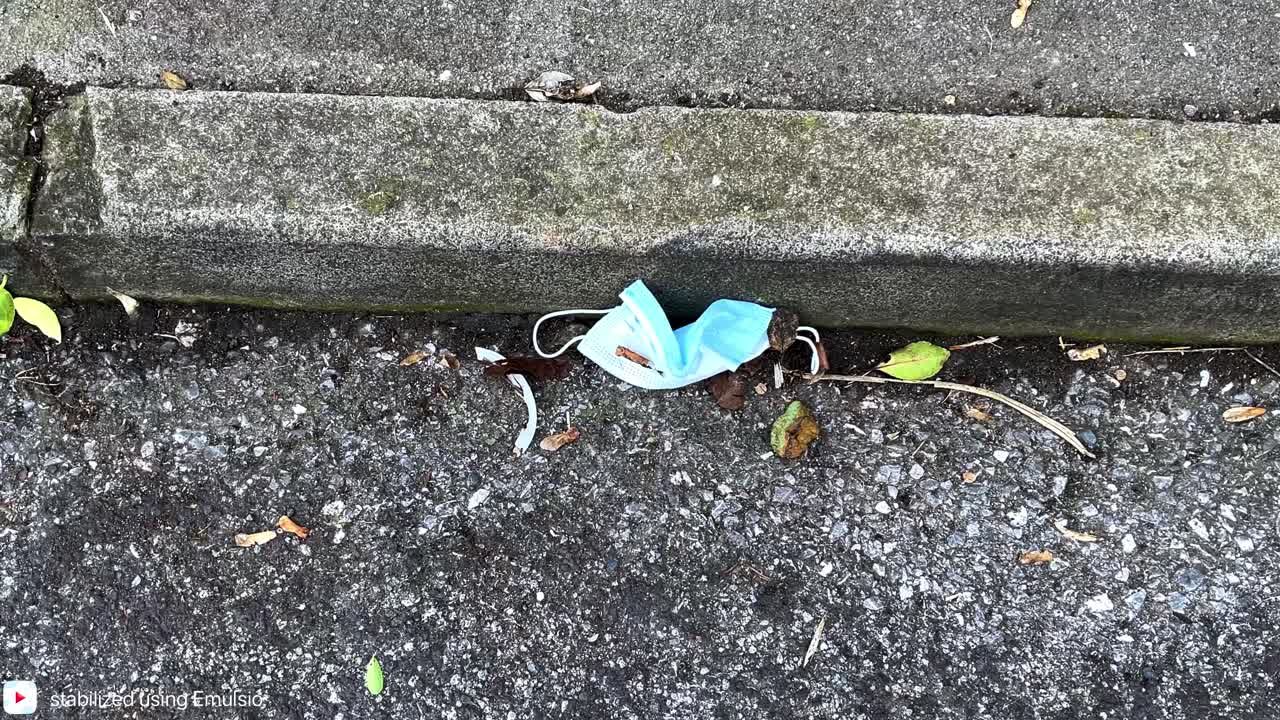 Medical grade face mask abandoned in the street, pandemic waste, biohazard waste. 4K 60ffs