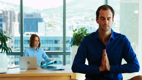 male executive meditating at his desk