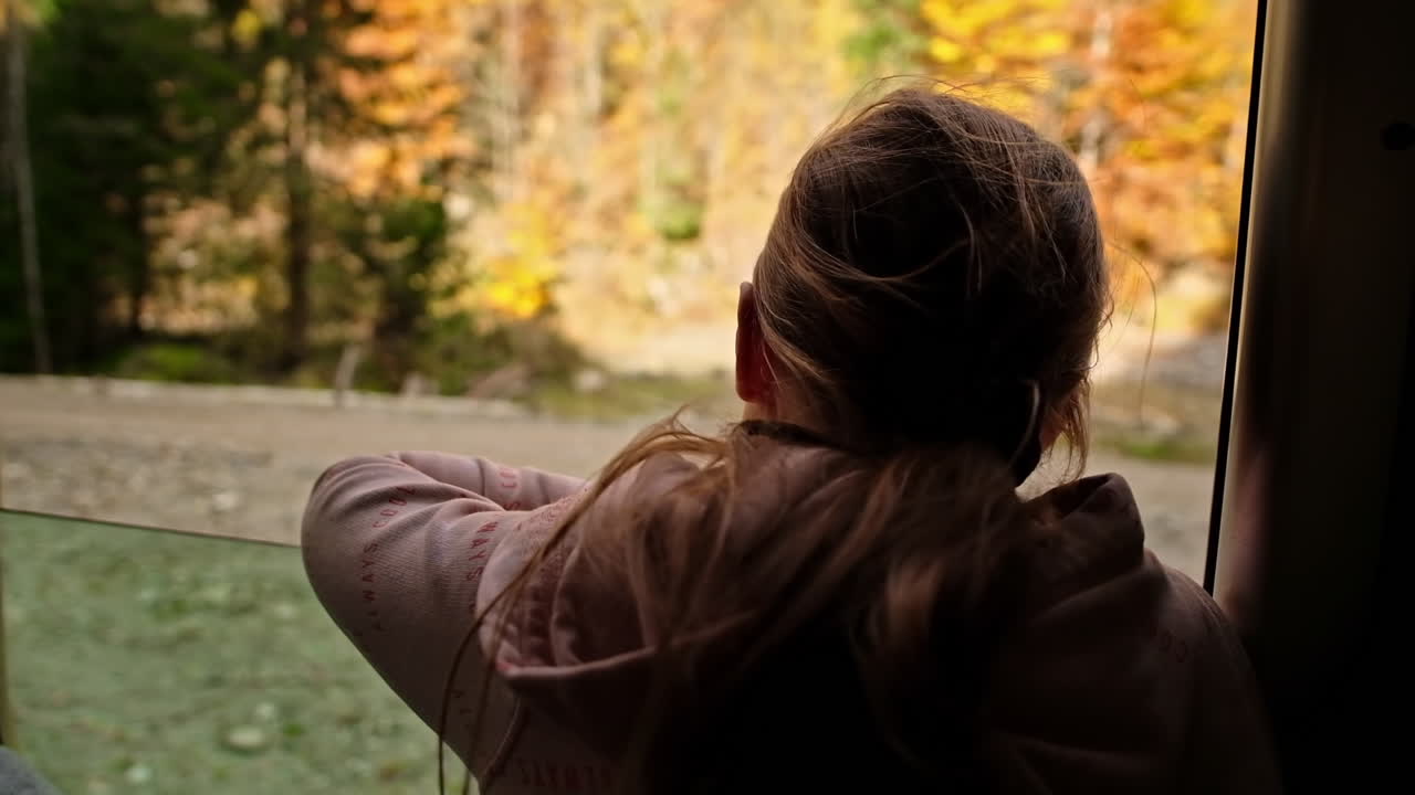 Woman leaned out of the window of the steam train Mocanita moving through a forest, Romania. Slow motion