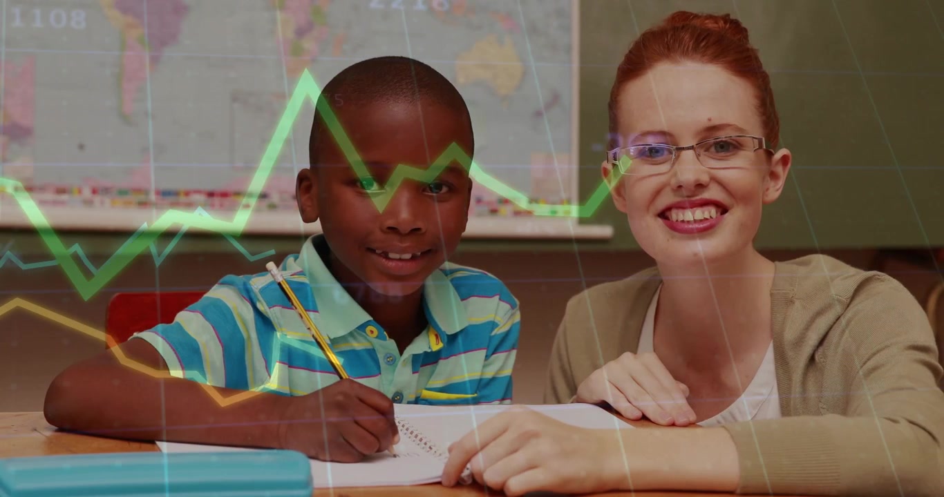 Boy writing notes while teacher guiding, showing classroom charts and percentages on map chalkboard