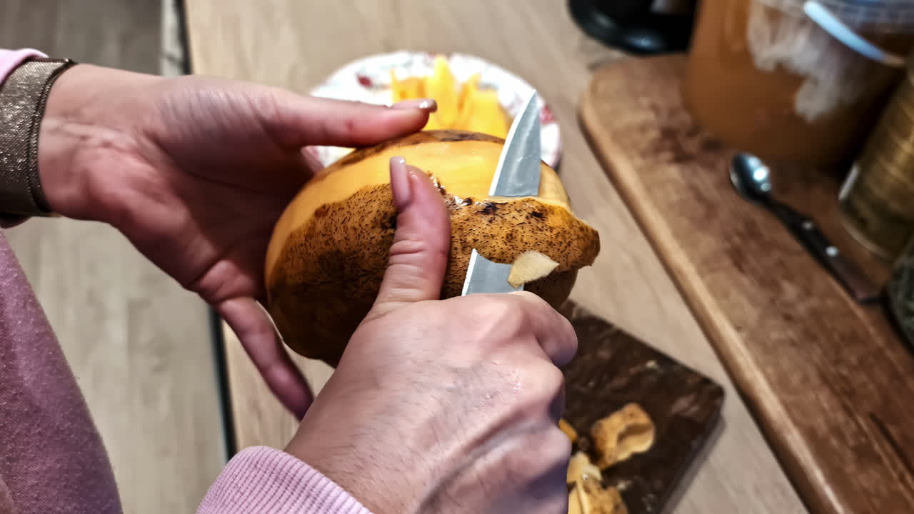 Close-up of a woman peeling a potato in the kitchen, preparing it for cooking with care.