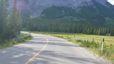 Hermosa-Vista-Del-Paisaje-De-La-Carretera-Local-Entre-El-Hermoso-Parque-Nacional-Natural-En-Banff,-Canadá-Con-La-Montaña-Rocosa-Y-El-Bosque-De-Pinos-En-El-Fondo-Durante-El-Día-De-Verano,-Alberta,-Canadá