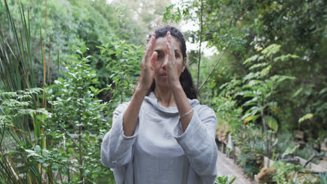 focused biracial woman practicing yoga in sunny garden, slow motion