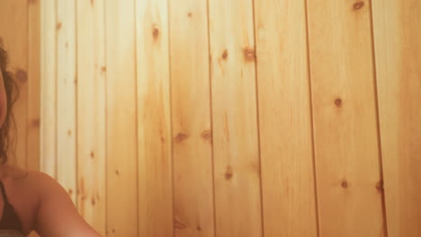 close up of sisters leaning against wood paneled wall, one gazing lovingly at sibling while soft backlight creates warm haze over wet curls, capturing tender connection