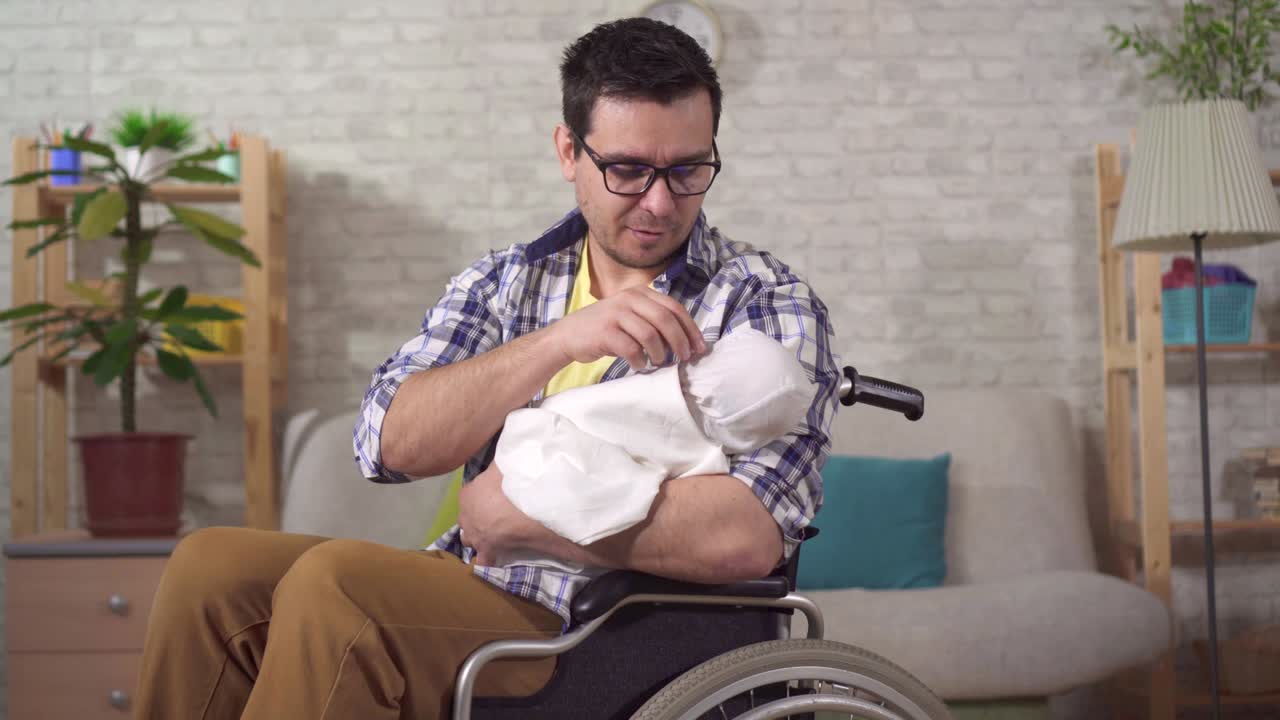 retrato joven padre es un hombre discapacitado en una silla de ruedas con un recién nacido en sus manos