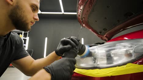 headlight polishing, processing of car lights. a car service worker polishes the headlight of a passenger car. professional polishing.