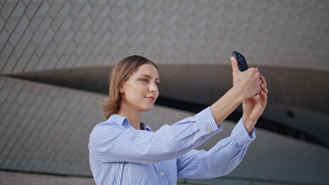 Woman taking selfie smartphone near modern architecture closeup. Stylish lady