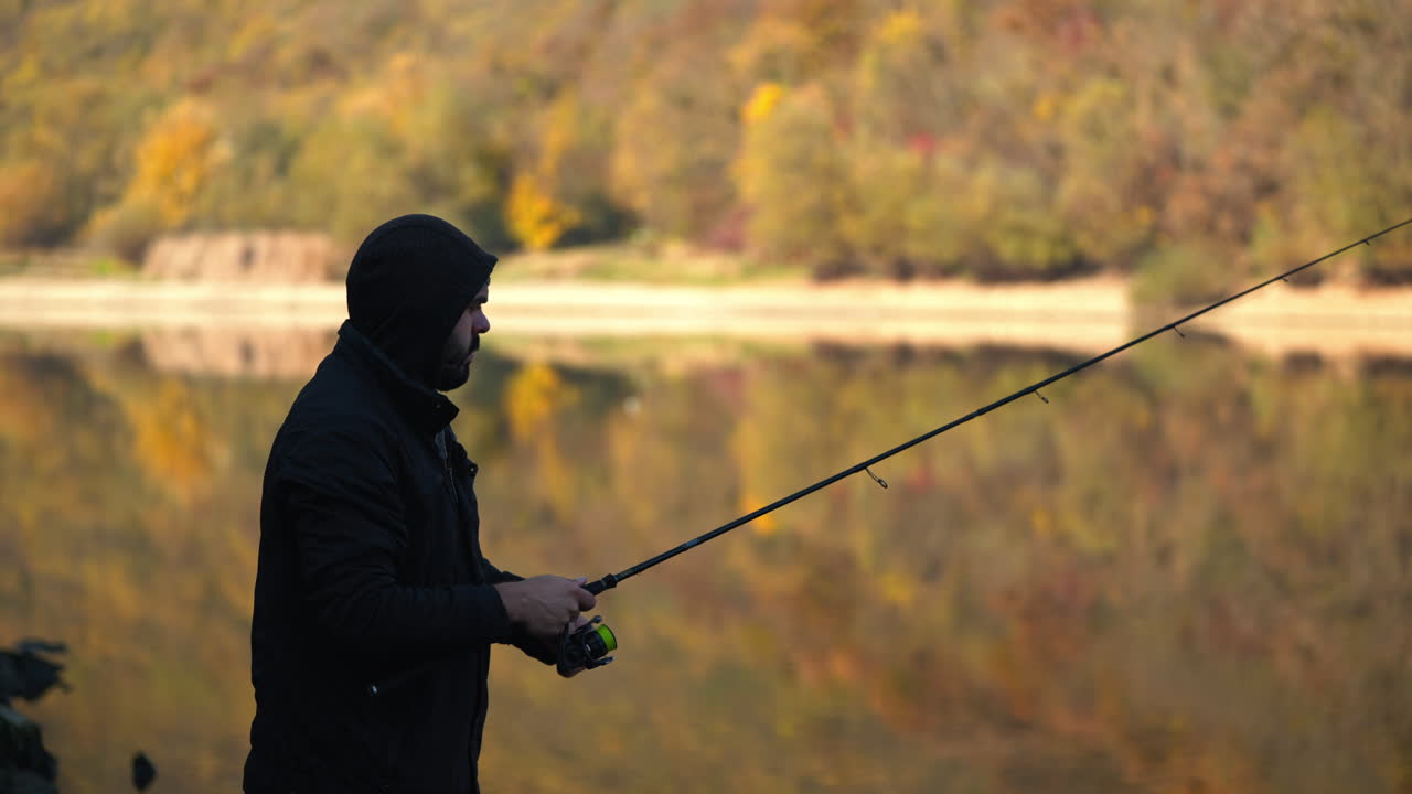 Pria memancing di tepi danau pada musim gugur.