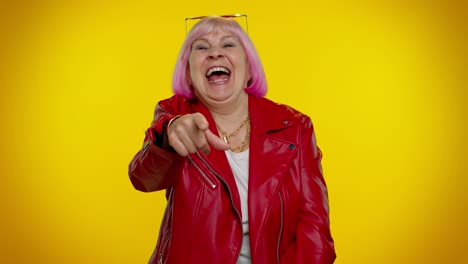 anciana divertida mujer señalando con el dedo a la cámara riendo en voz alta de apariencia ridícula broma divertida