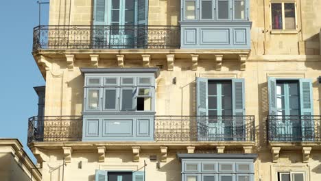 rustic limestone townhouses in malta with blue windows and balconies