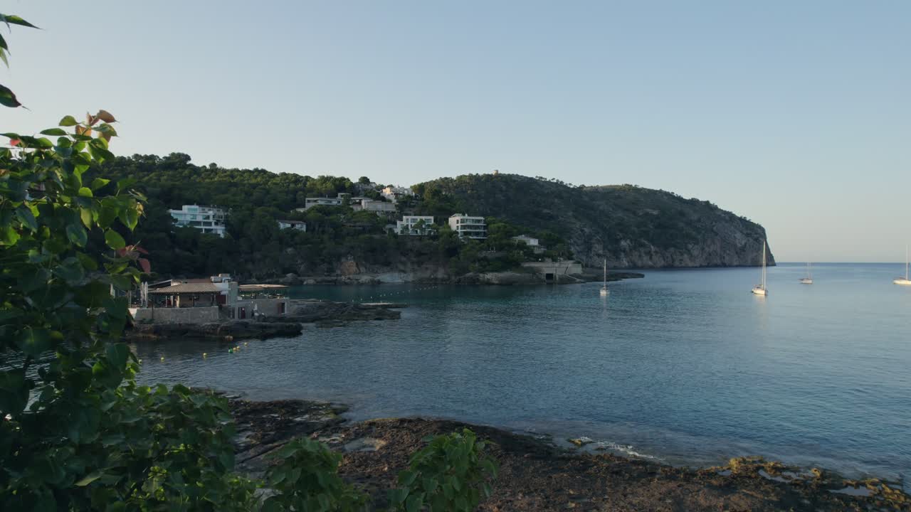 Drohne steigt vom Poolbereich auf, um den Strand, Boote und Hügel am Horizont zu zeigen, Mallorca, Spanien