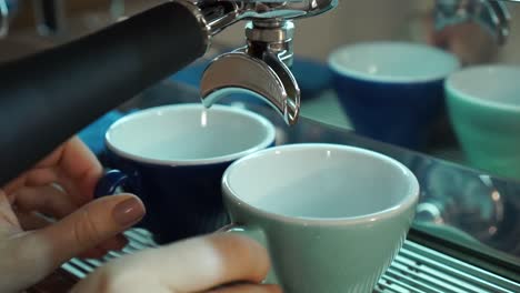 professional female barista prepares two porcelain cappuccino cups of espresso