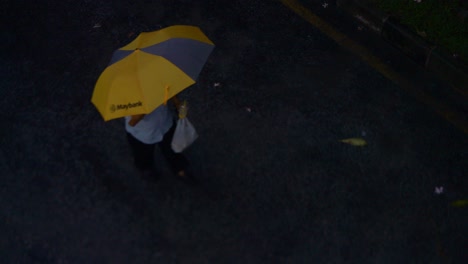 man walking under umbrella in kuala lumpur, malaysia. rainy day scenes.