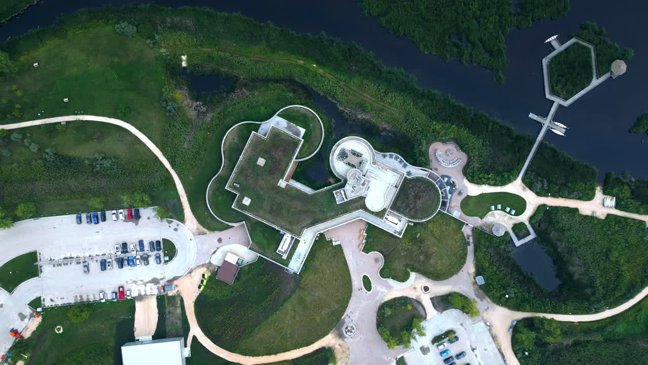 Top-down aerial approach to circular green-roof building amid wetlands