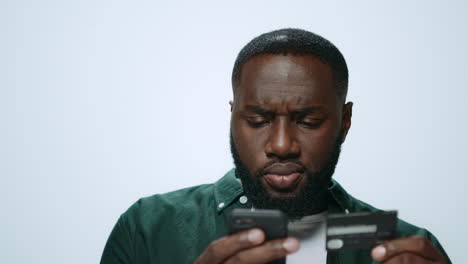 portrait of serious african man shopping online on smartphone in studio