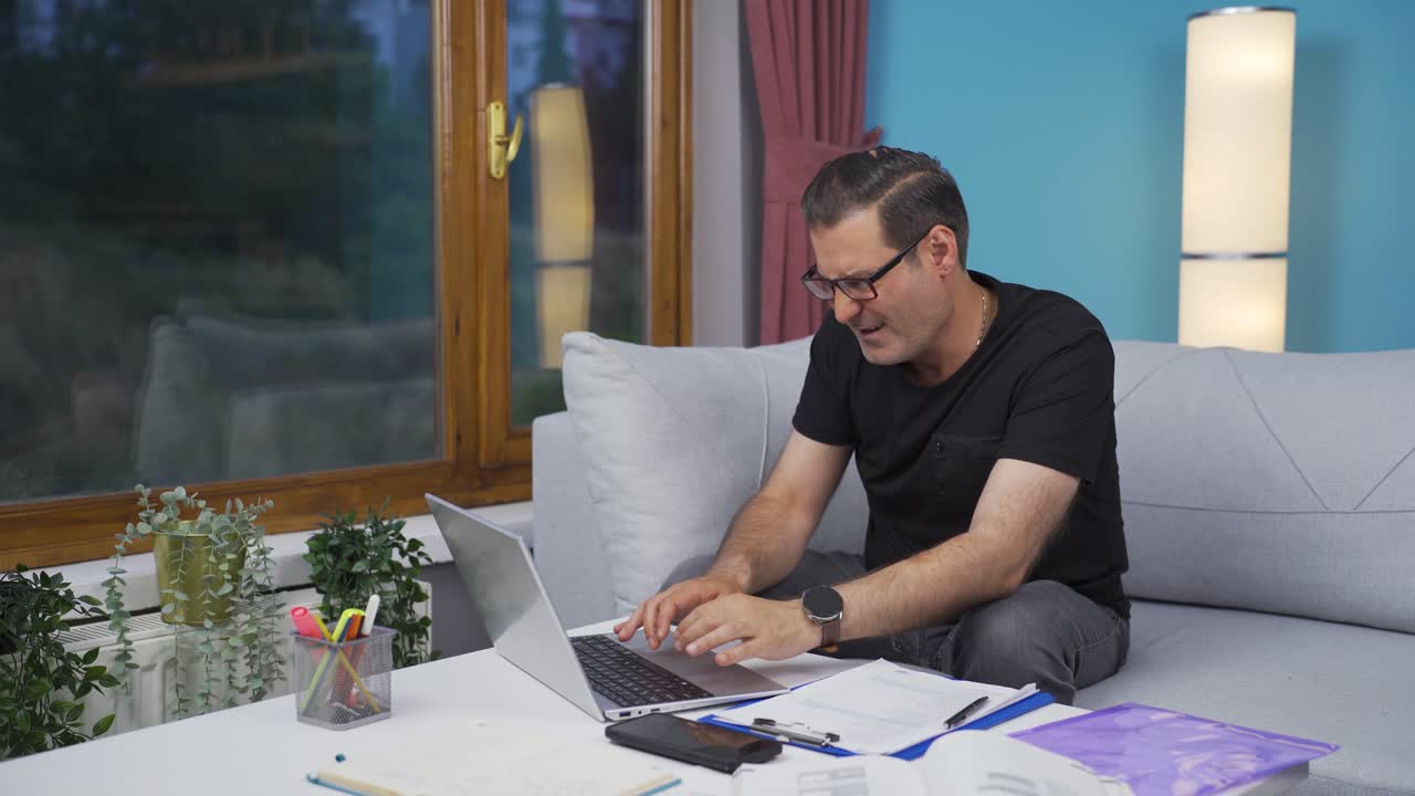 Home office worker man working on laptop stressed.