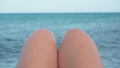 Static-shot-of-the-sea-horizon-with-woman's-knees-in-front
