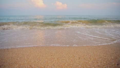 close up of sand and waves lapping shore on a tropical beach in thailand at koh samui tropical island, waves breaking on sandy beach detail shot, background with copy space