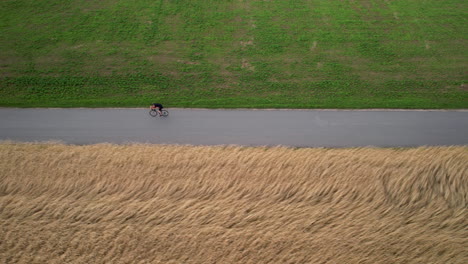 Professional-Road-Cyclist-Cycling-Through-Agricultural-Fields---Bird's-eye-Aerial-Tracking-Motion-View