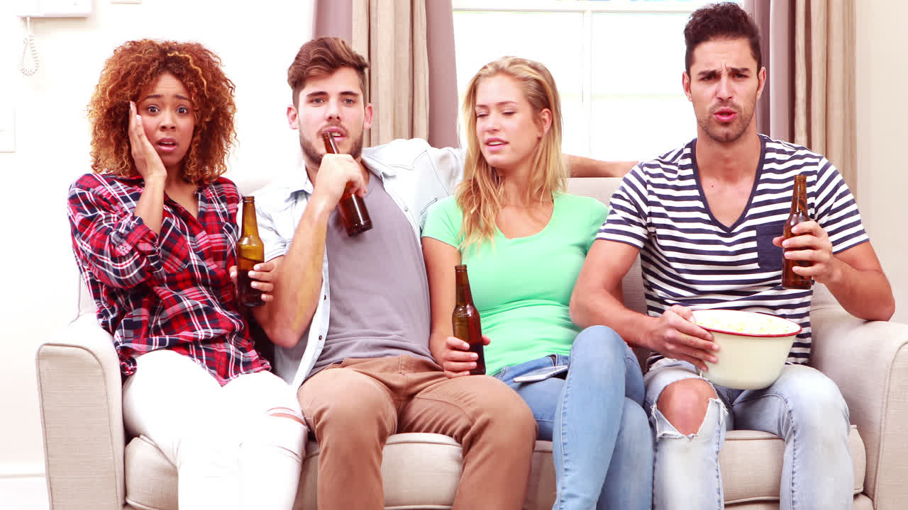 웃는 친구 들 이 팝콘 을 먹고 맥주 를 마시면서 tv 를 보고 있다