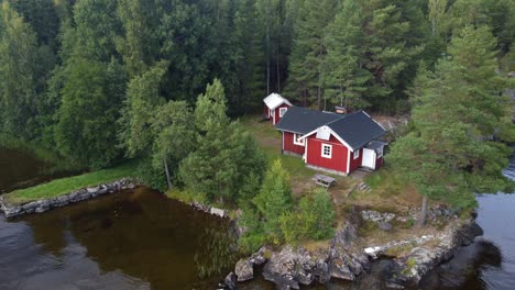 Zoom-Lento-De-Una-Típica-Cabaña-Roja-Sueca-En-Un-Lago-Rodeado-De-Pinos-Y-Un-Lago-Oscuro