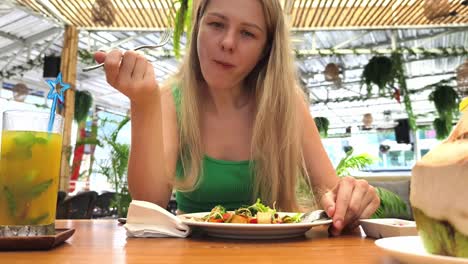 mujer comiendo ensalada en un café tropical