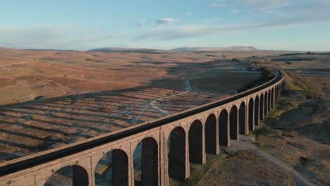 Railway-bridge-flyover-of-Ribblehead-Viaduct-at-sunset-in-winter-with-long-shadows