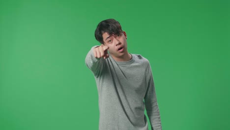 an angry asian man scolding while standing on green screen in the studio