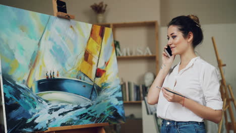 woman artist looking at a painting of a sailboat