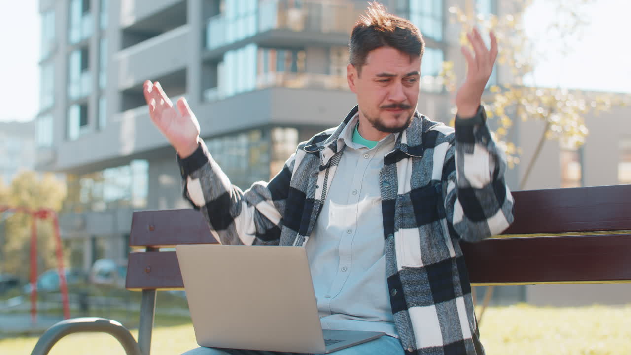 Caucasian mature man using laptop browsing loses lottery results bad news sitting in city street