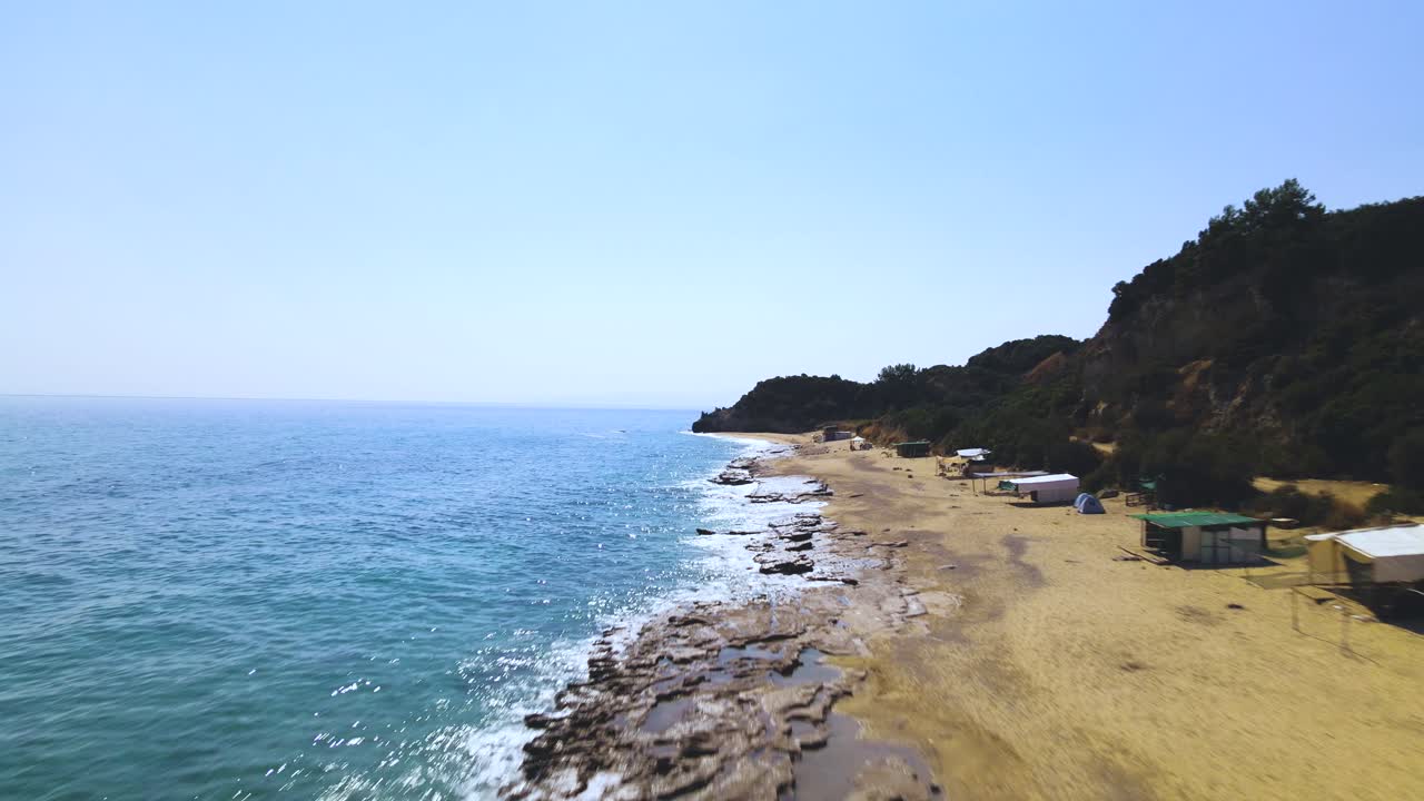 그리스 마케도니아 카발라의 모래 해변과 암석 위로 뒤로 움직이는 공중 드론 클립
