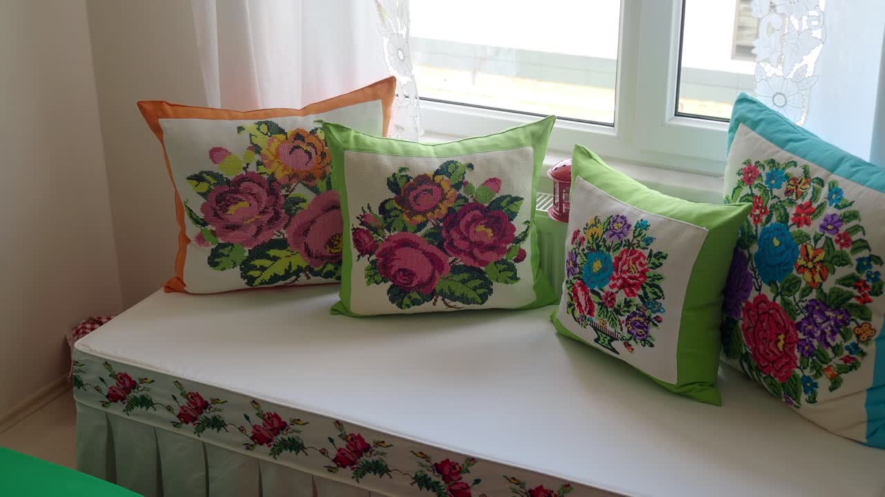 almohadas florales bordadas de colores en un asiento de la ventana