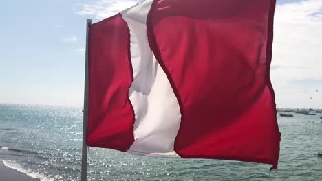 bandera peruana en cámara lenta, ondeando durante un día soleado en una playa