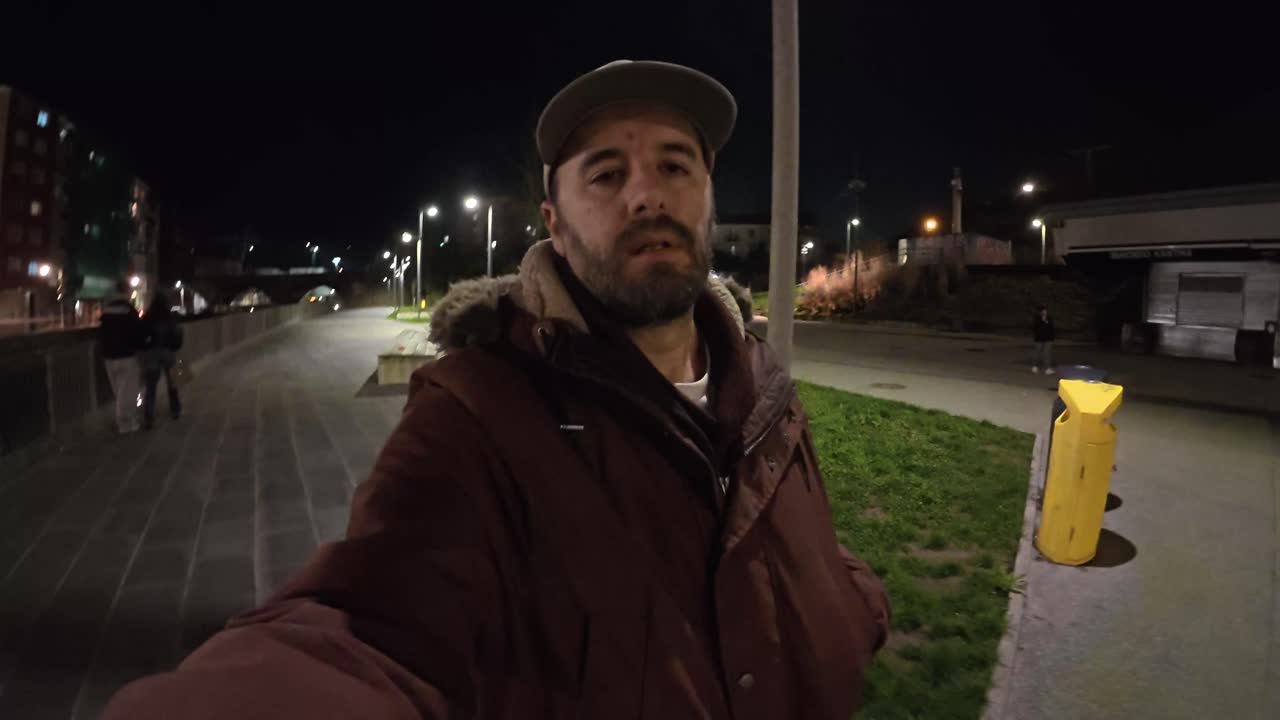 Uomo che si filma mentre cammina per una strada cittadina di notte