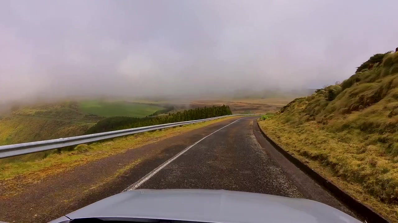 Guida panoramica in auto lungo una strada di montagna tortuosa circondata da paesaggi vulcanici nebbiosi sull'isola di Flores, Azzorre, Portogallo.