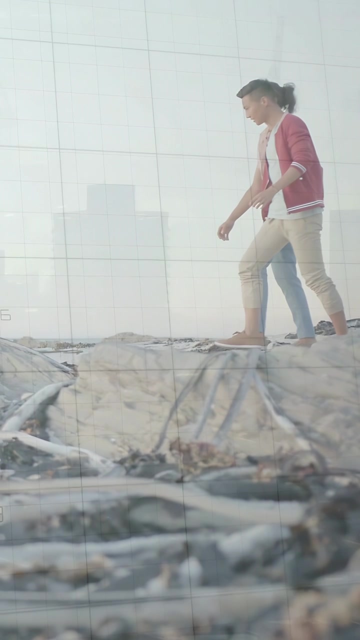Video vertical: Dos hombres entrando por la derecha, el líder de rojo caminando por una cornisa, su compañero siguiendo el ritmo para la filmación.