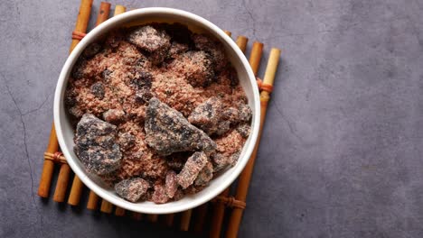 Himalayan-black-salt-rock-crystals,-kala-namak-in-a-container-on-table